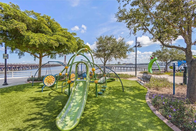 surrounding community with a water view, a playground, and a lawn