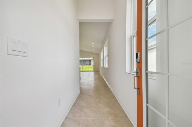 hallway featuring light tile patterned flooring and lofted ceiling