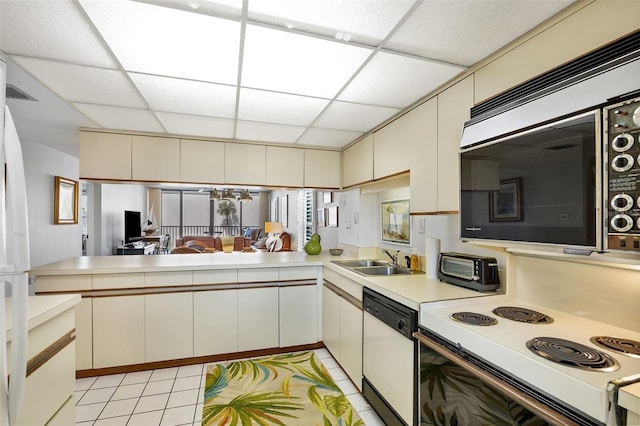 kitchen with sink, kitchen peninsula, cream cabinets, white appliances, and a paneled ceiling