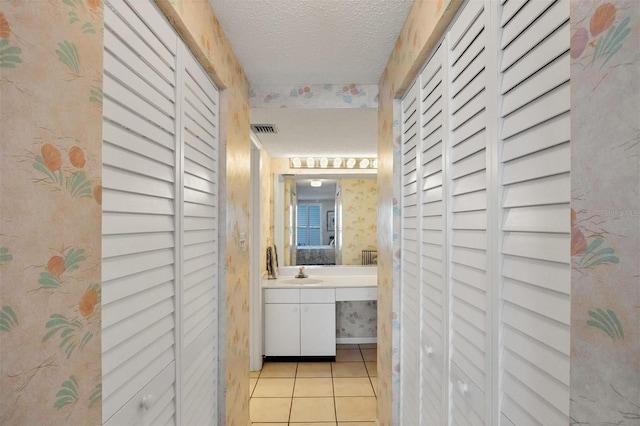 bathroom with tile patterned flooring, vanity, and a textured ceiling