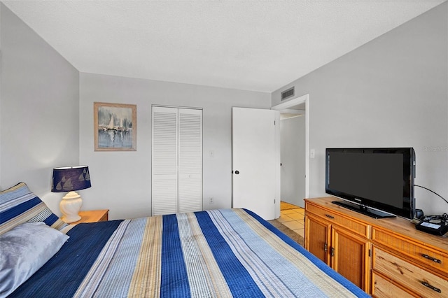 bedroom featuring a closet, light tile patterned floors, and a textured ceiling