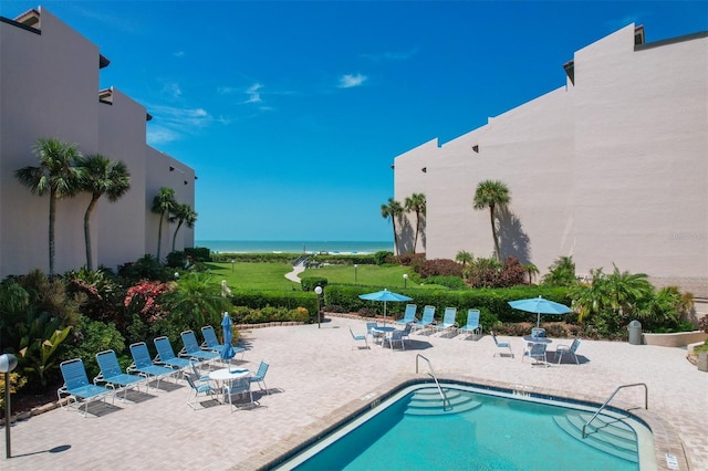 view of swimming pool featuring a patio and a water view