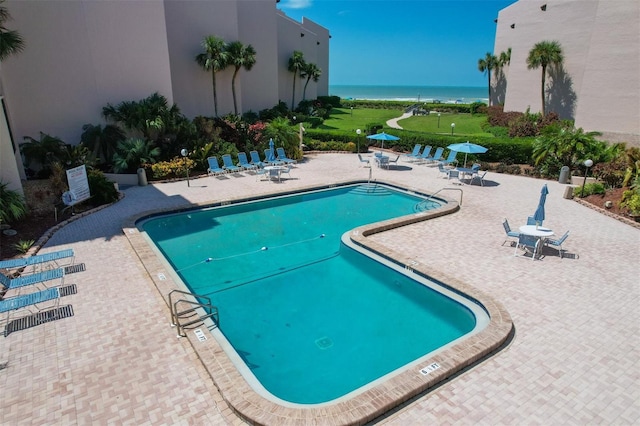 view of swimming pool with a water view and a patio area