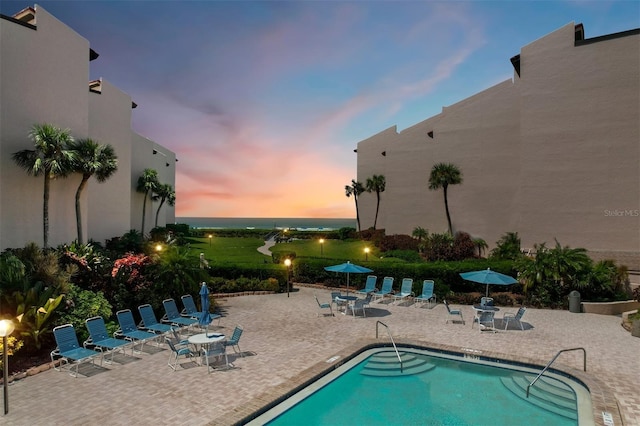 pool at dusk featuring a patio