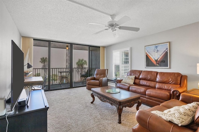 carpeted living room with a textured ceiling, expansive windows, and ceiling fan