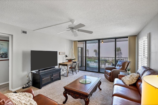 carpeted living room with a textured ceiling, a wall of windows, and ceiling fan