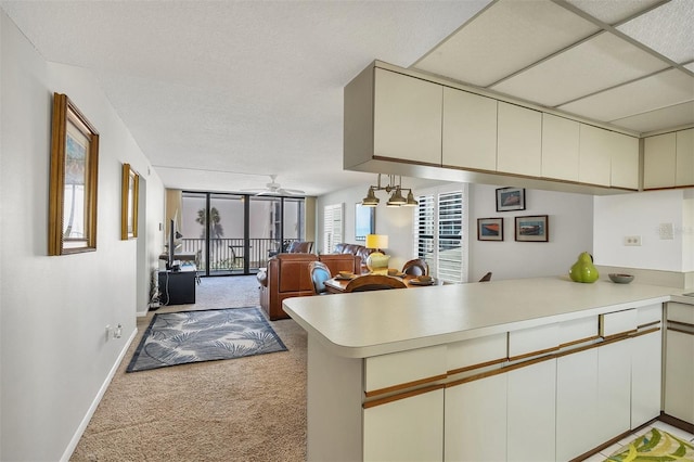 kitchen featuring kitchen peninsula, carpet flooring, ceiling fan, and a paneled ceiling