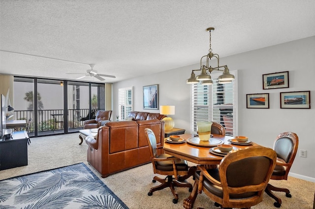 carpeted dining room with ceiling fan with notable chandelier, expansive windows, and a textured ceiling