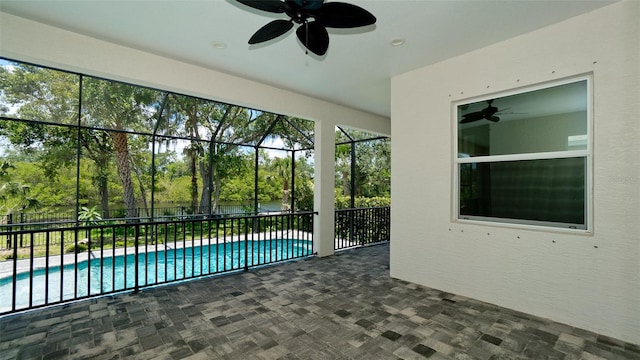 view of swimming pool featuring ceiling fan, a lanai, and a patio area