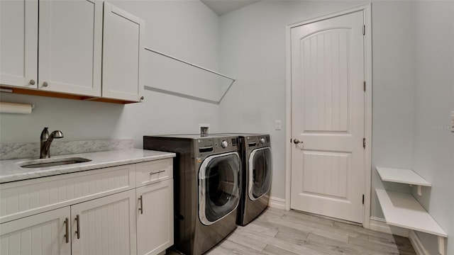 laundry area with sink, separate washer and dryer, light hardwood / wood-style floors, and cabinets