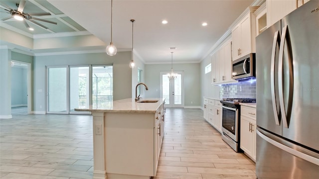 kitchen with appliances with stainless steel finishes, decorative light fixtures, white cabinets, and an island with sink