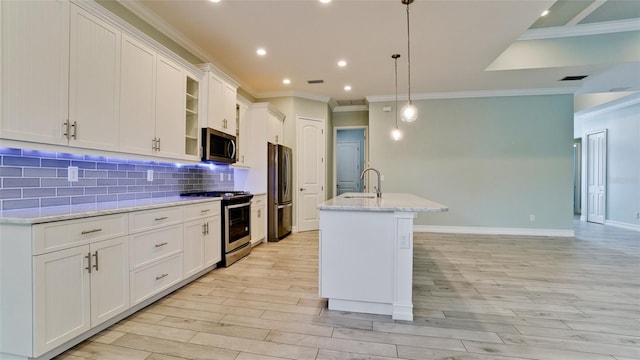 kitchen featuring a center island with sink, sink, white cabinets, decorative light fixtures, and appliances with stainless steel finishes