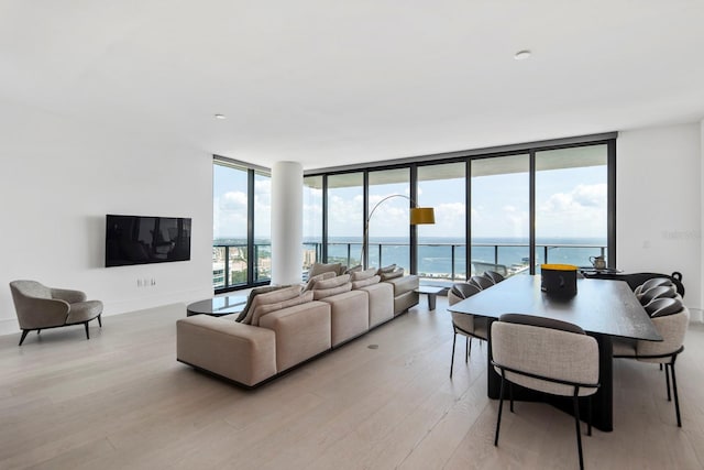 living room with a water view, expansive windows, and light wood-type flooring