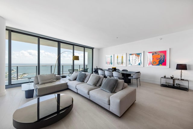 living room with a water view, expansive windows, and light hardwood / wood-style flooring