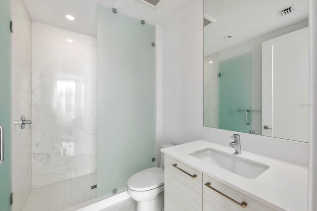 bathroom featuring toilet, vanity with extensive cabinet space, and tiled shower