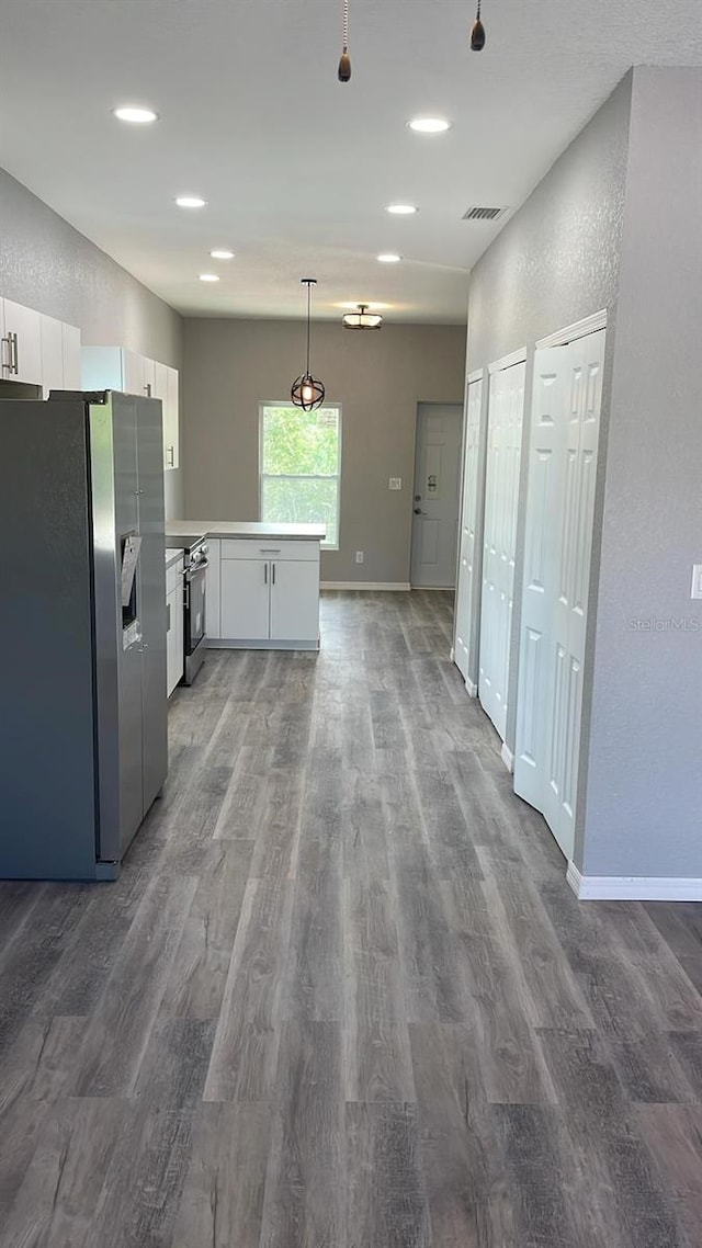 kitchen with stainless steel appliances, dark hardwood / wood-style floors, kitchen peninsula, and white cabinetry