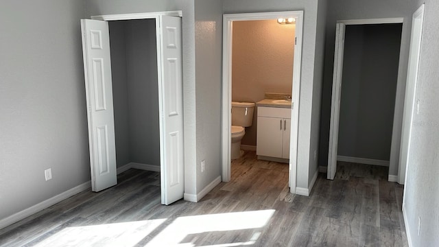 unfurnished bedroom featuring wood-type flooring, connected bathroom, and sink