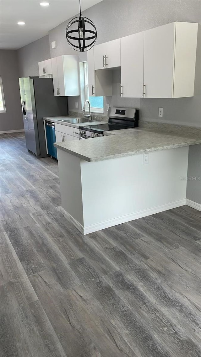 kitchen featuring decorative light fixtures, appliances with stainless steel finishes, dark hardwood / wood-style floors, and kitchen peninsula