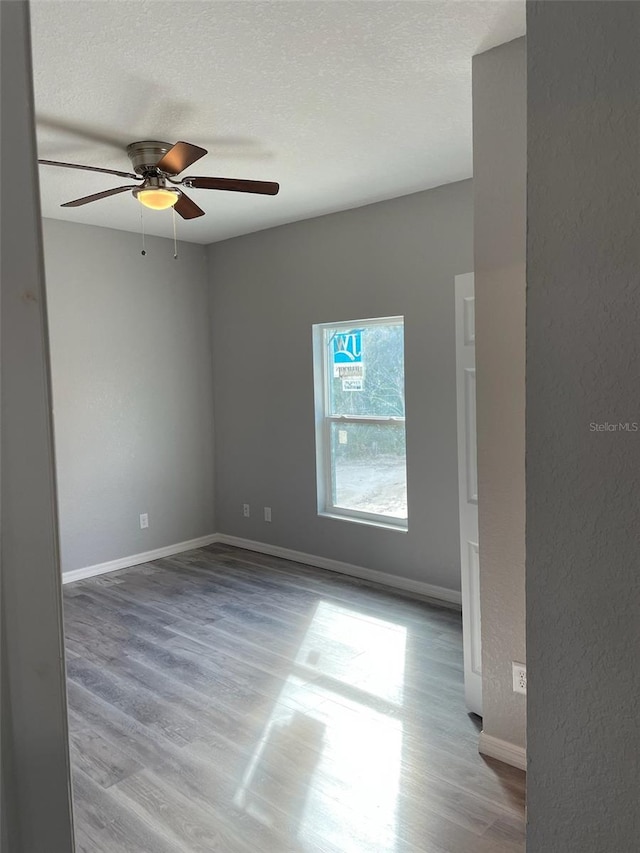 unfurnished room with ceiling fan, a textured ceiling, and light hardwood / wood-style flooring