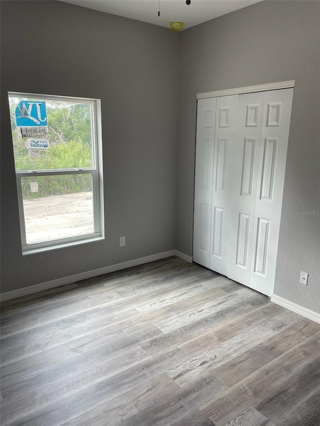 unfurnished bedroom with light wood-type flooring and a closet