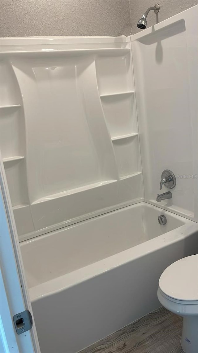 bathroom with toilet, shower / bath combination, and hardwood / wood-style flooring