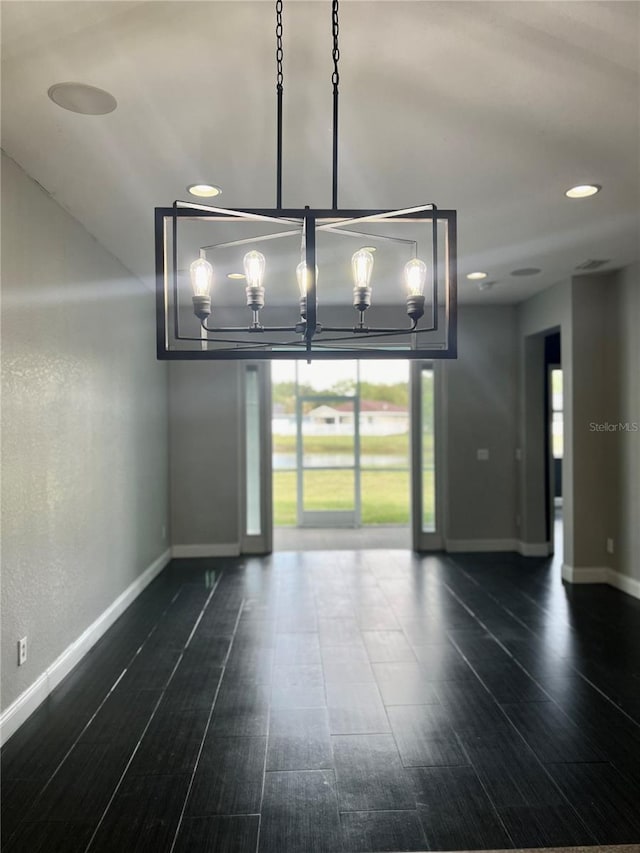 spare room featuring dark hardwood / wood-style floors and a notable chandelier