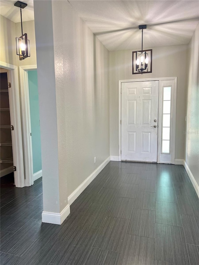 foyer entrance featuring an inviting chandelier and dark tile floors