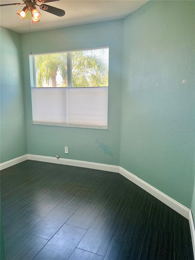 unfurnished room with dark wood-type flooring, ceiling fan, and a wealth of natural light