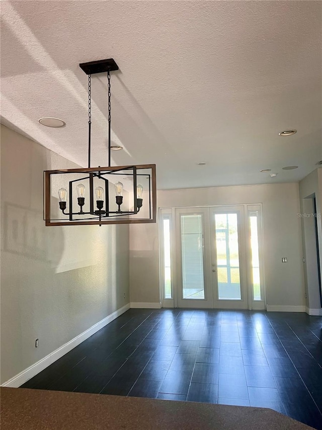 spare room featuring an inviting chandelier, a textured ceiling, and dark hardwood / wood-style floors