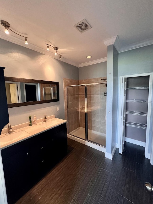 bathroom featuring vanity with extensive cabinet space, dual sinks, walk in shower, and crown molding