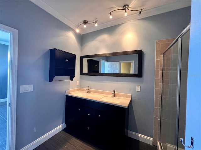 bathroom with an enclosed shower, hardwood / wood-style floors, track lighting, vanity with extensive cabinet space, and crown molding