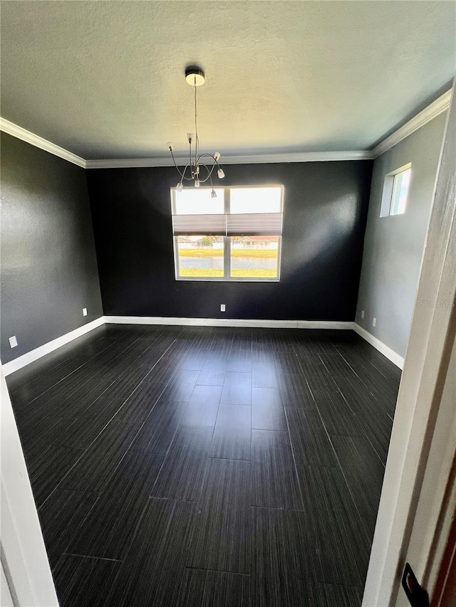 empty room with a textured ceiling, crown molding, dark hardwood / wood-style floors, and an inviting chandelier