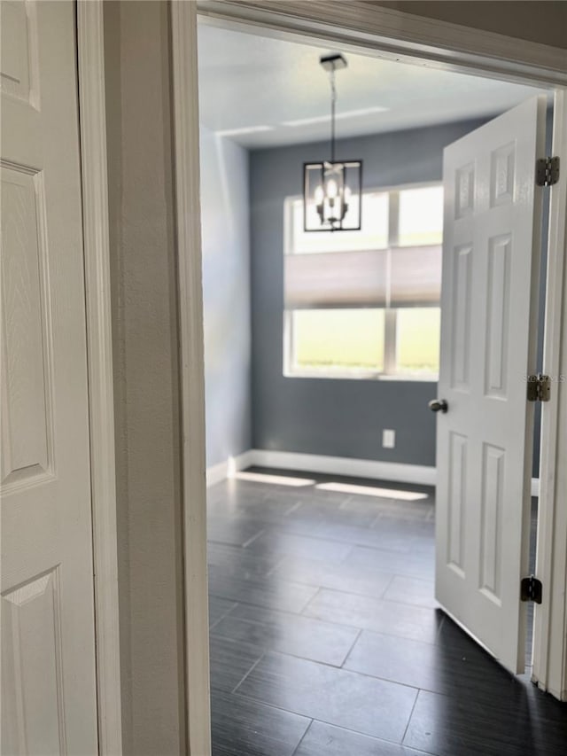 unfurnished dining area with a notable chandelier and dark wood-type flooring