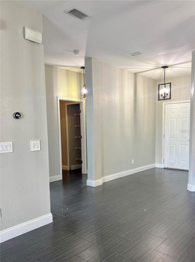 spare room featuring a chandelier and dark wood-type flooring