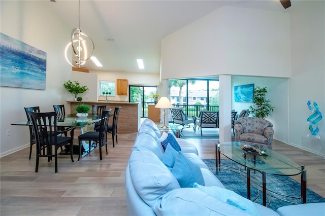 living area featuring light wood-style floors, a high ceiling, and baseboards