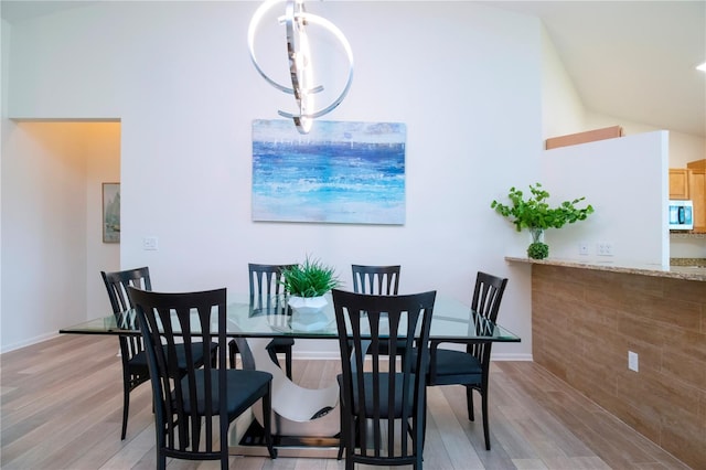 dining room with light hardwood / wood-style floors and high vaulted ceiling