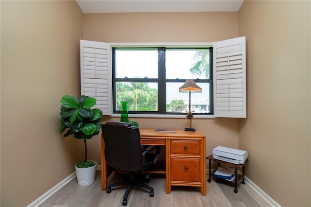 office space with light wood-style floors, a healthy amount of sunlight, and baseboards