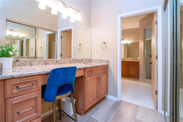 bathroom with a shower stall, baseboards, wood finished floors, and vanity