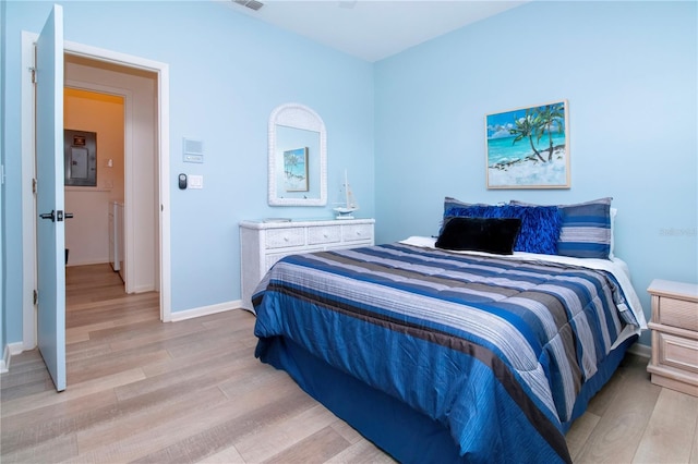 bedroom featuring light wood-style floors, electric panel, visible vents, and baseboards