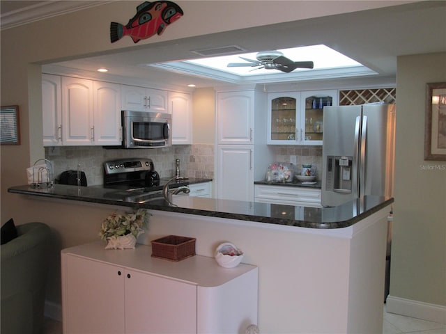 kitchen with kitchen peninsula, tasteful backsplash, ceiling fan, white cabinets, and appliances with stainless steel finishes