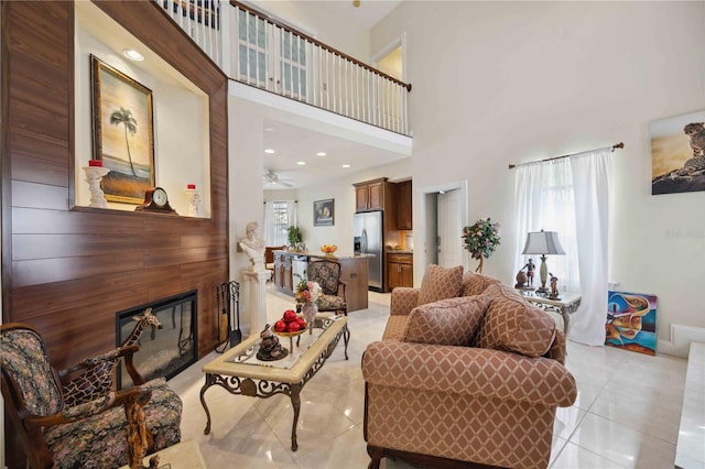 tiled living room with ceiling fan and a towering ceiling