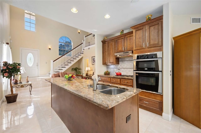 kitchen featuring light tile floors, light stone countertops, tasteful backsplash, appliances with stainless steel finishes, and sink