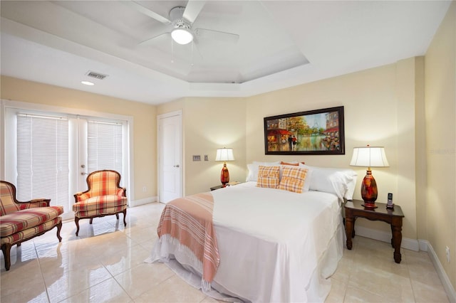 tiled bedroom with a tray ceiling and ceiling fan