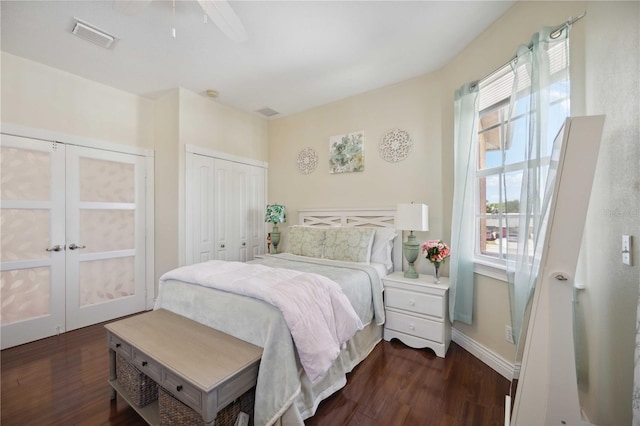 bedroom featuring ceiling fan, multiple closets, and dark wood-type flooring