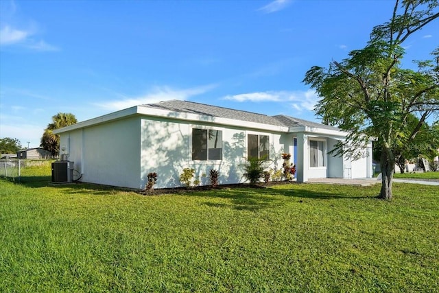 rear view of house featuring central AC unit and a yard