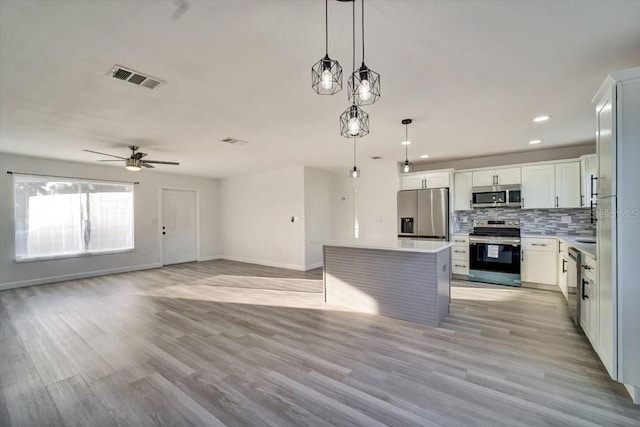 kitchen featuring pendant lighting, ceiling fan, appliances with stainless steel finishes, light hardwood / wood-style floors, and white cabinetry