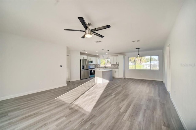 unfurnished living room featuring light hardwood / wood-style floors, ceiling fan with notable chandelier, and sink