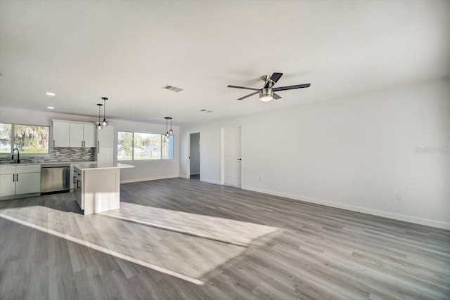 empty room with light hardwood / wood-style floors, sink, and ceiling fan with notable chandelier