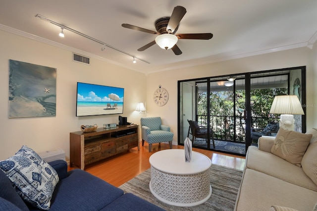 living room featuring rail lighting, crown molding, ceiling fan, and light wood-type flooring