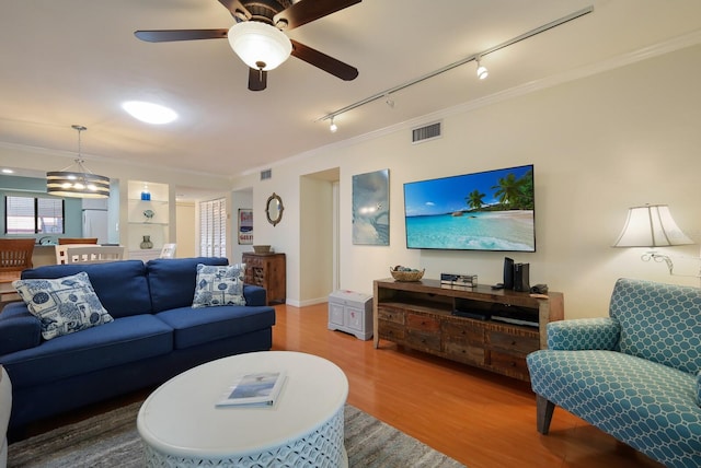 living room with ornamental molding, wood-type flooring, ceiling fan, and track lighting